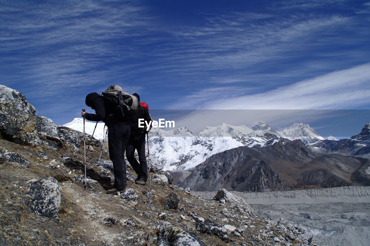 Rear view of people on snowcapped mountain against sky