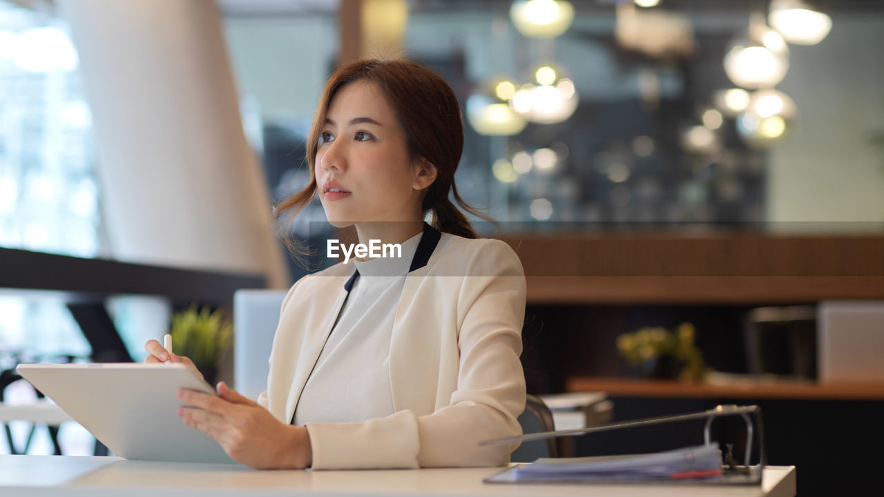 Young woman using mobile phone at table