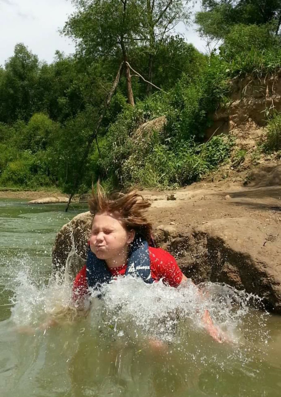 Boy diving in river against trees