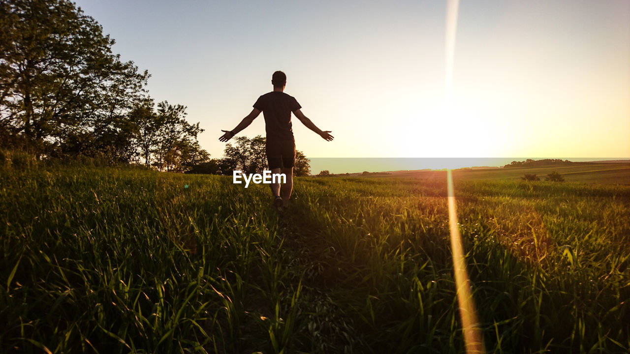 Rear view of man standing on field against sky