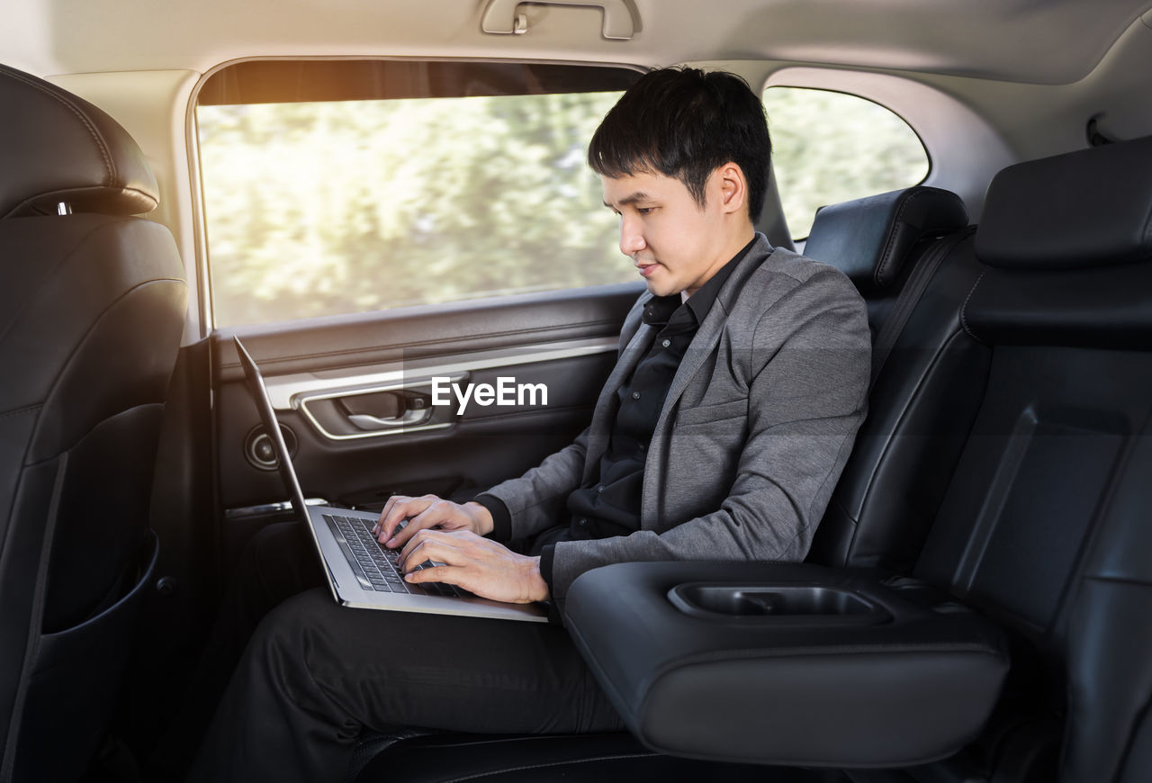 portrait of young woman using phone while sitting in car