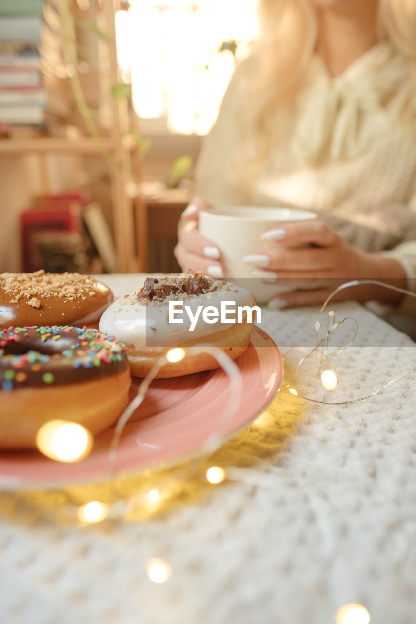 Woman enjoy in donuts and coffee in cozy home