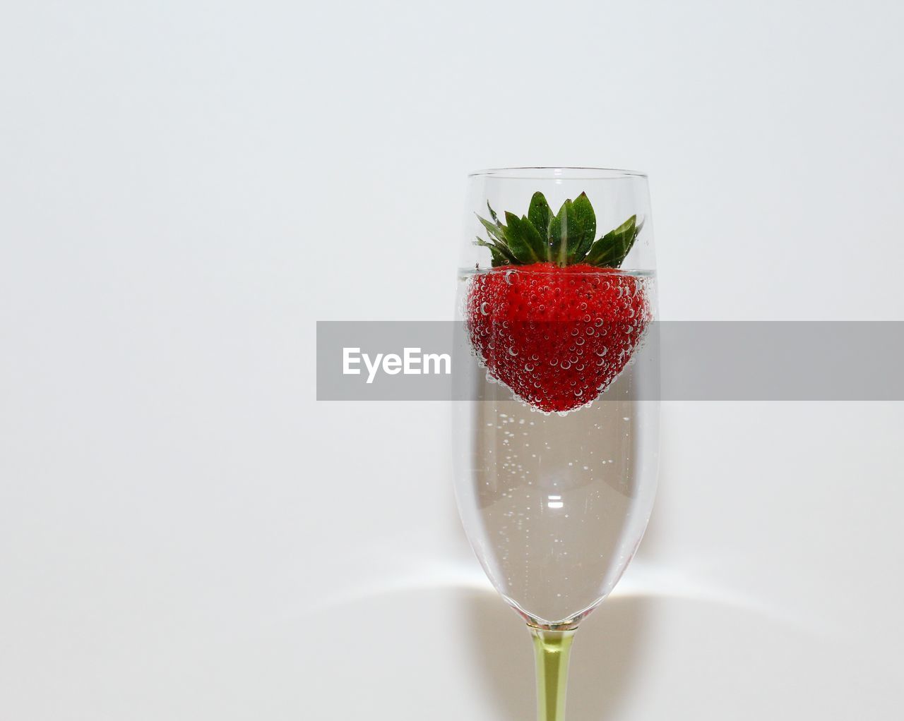 Close-up of strawberry in drink against white background