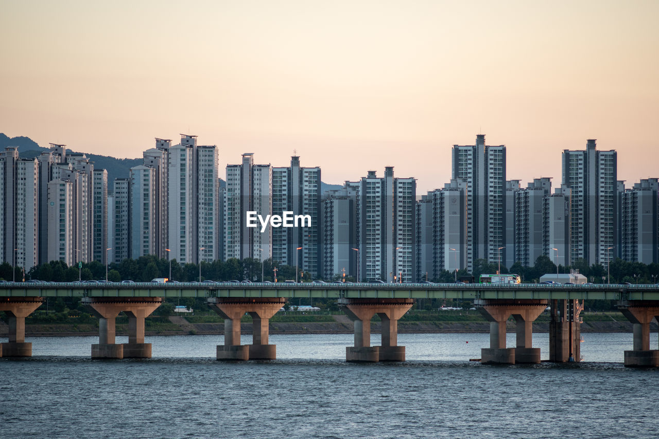 BRIDGE OVER RIVER AGAINST BUILDINGS IN CITY