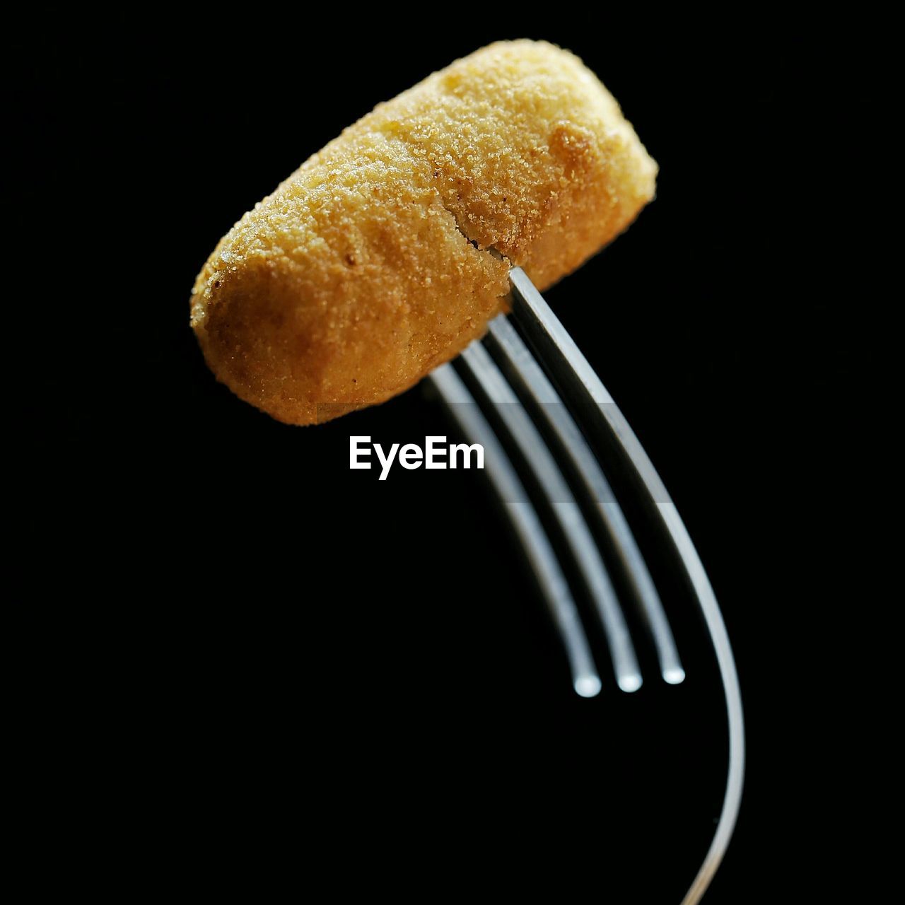 Close-up of breaded croquette with fork