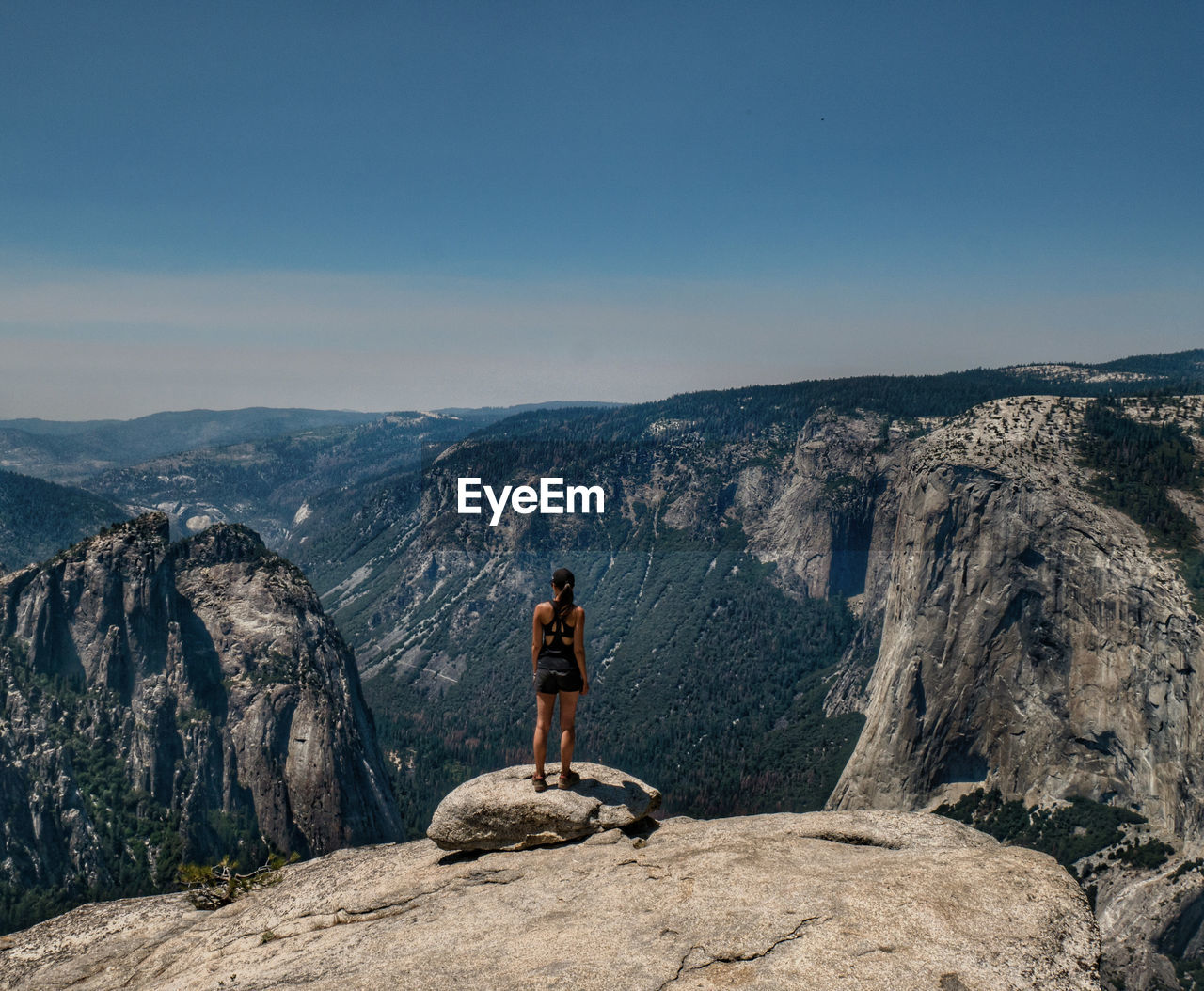 Rear view of young woman standing on mountain against sky