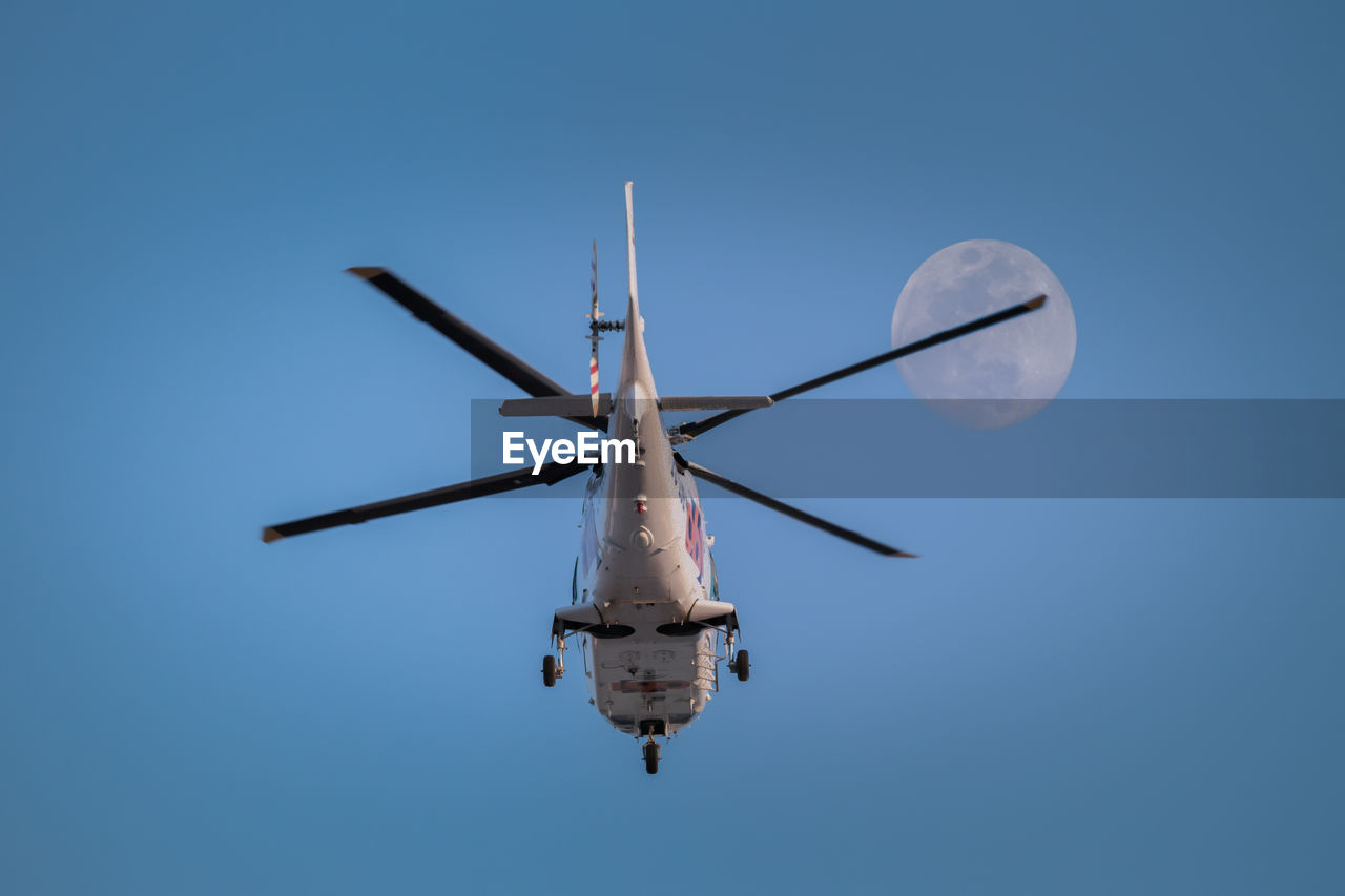 Helicopter in flight against clear sky and full moon