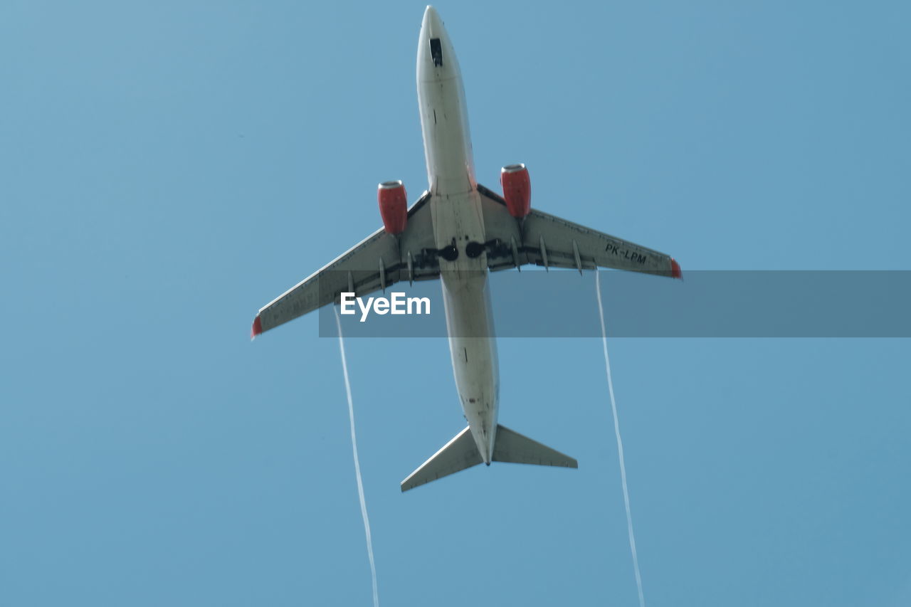 LOW ANGLE VIEW OF AIRPLANE AGAINST BLUE SKY