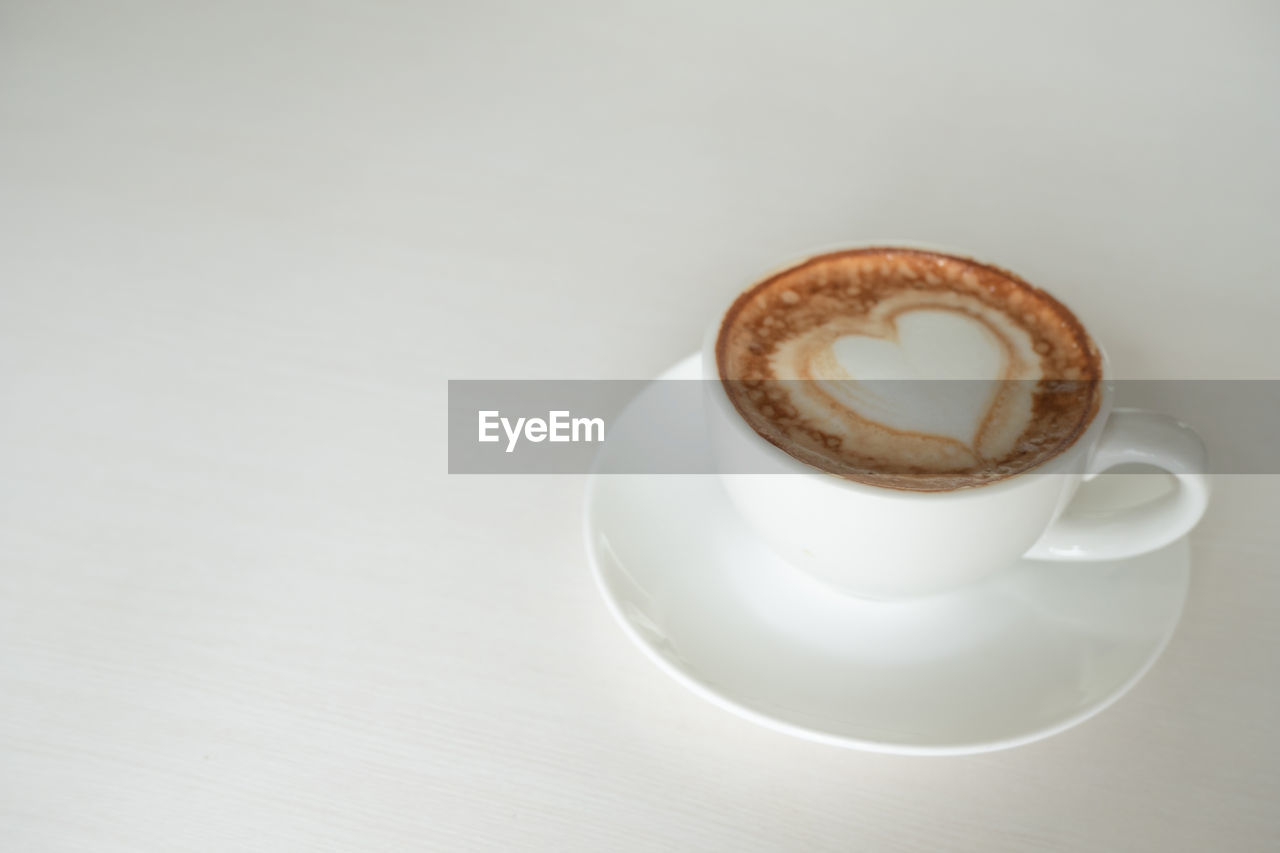 CLOSE-UP OF COFFEE CUP WITH SPOON AND SAUCER ON TABLE