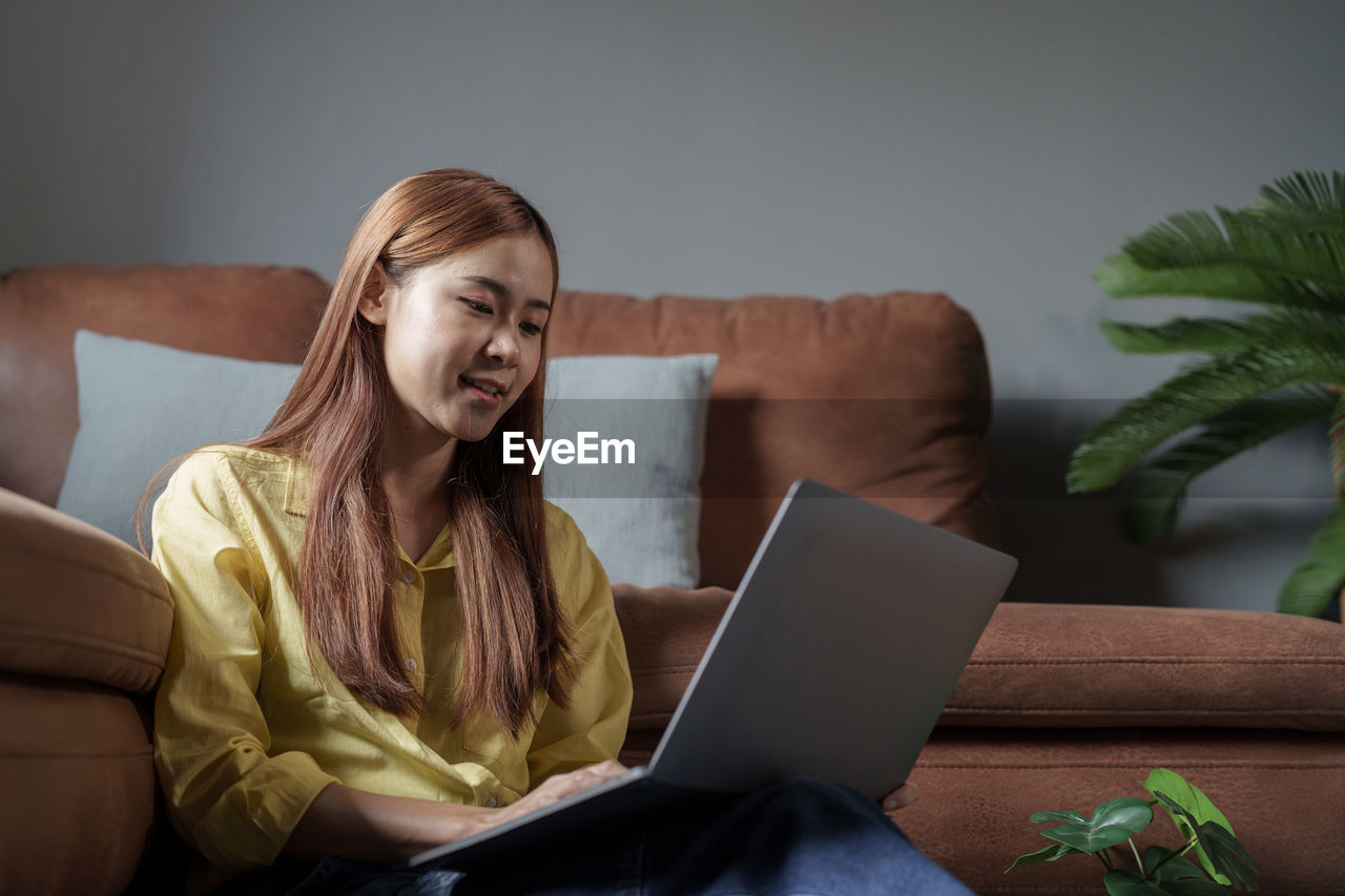 portrait of young woman using laptop while sitting on table