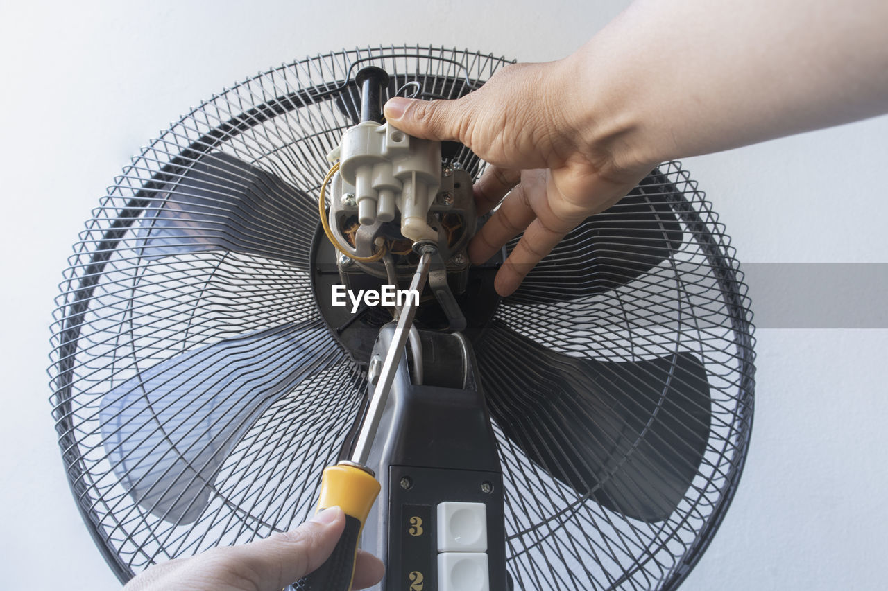 Cropped hands repairing electric fan