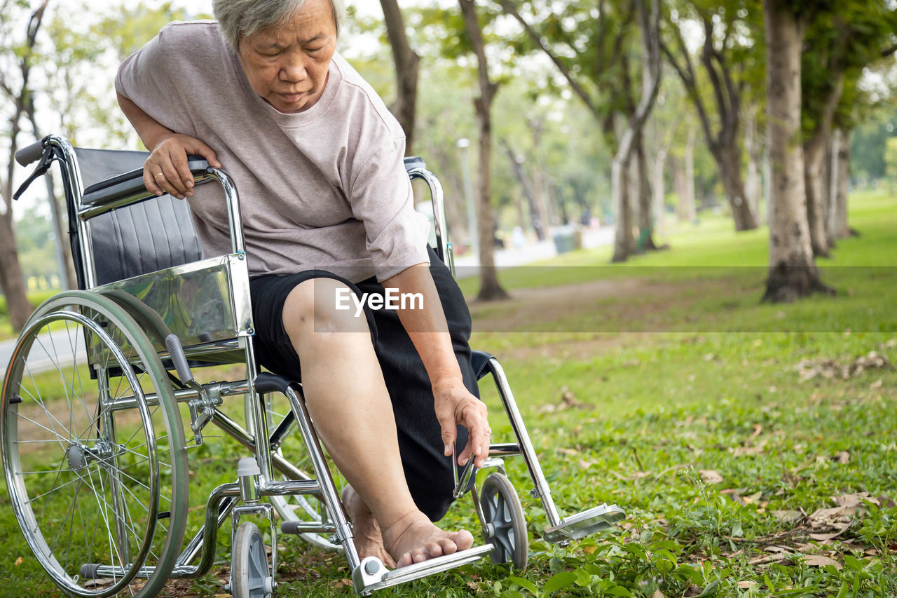 Senior woman sitting on wheelchair at park