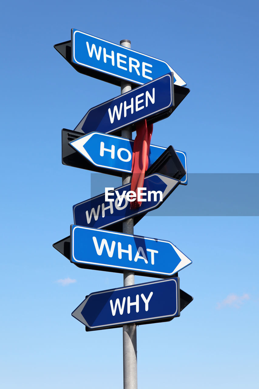 Road sign with question words isolated on blue sky background. what, who, why, how, when, where.