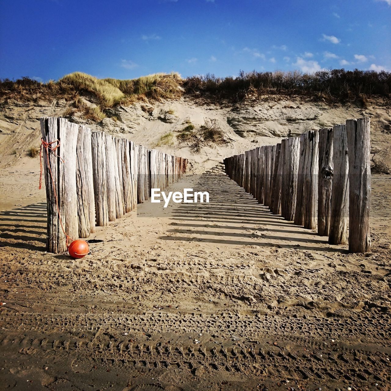 Wooden posts on beach against sky