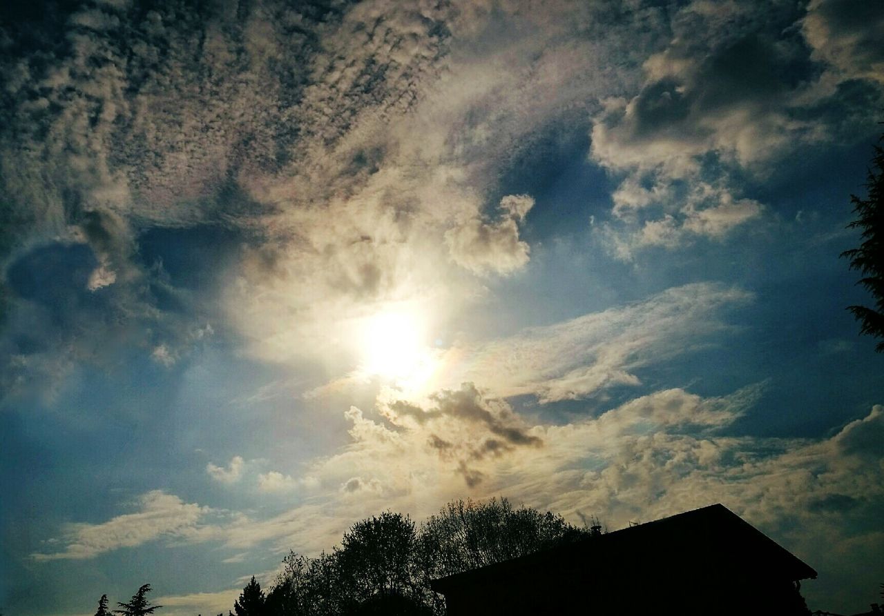 LOW ANGLE VIEW OF SUN SHINING THROUGH CLOUDS