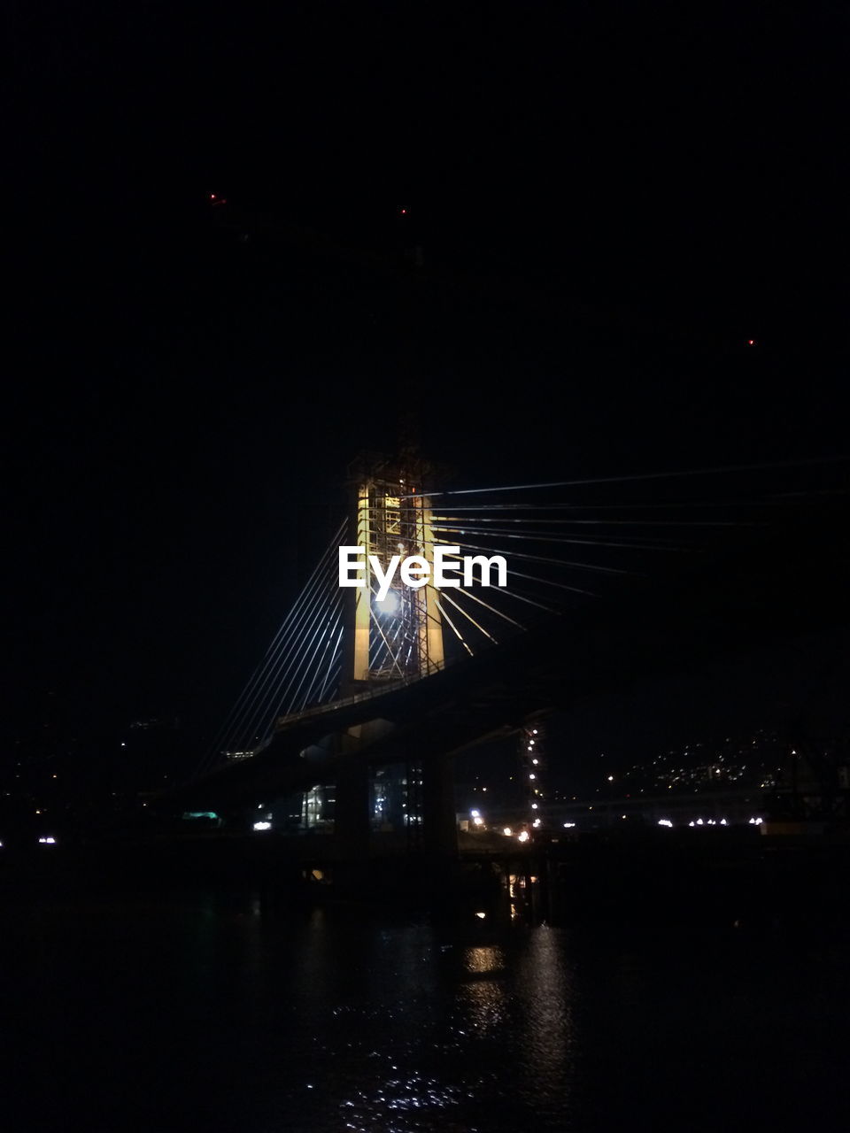 ILLUMINATED BRIDGE OVER RIVER AT NIGHT