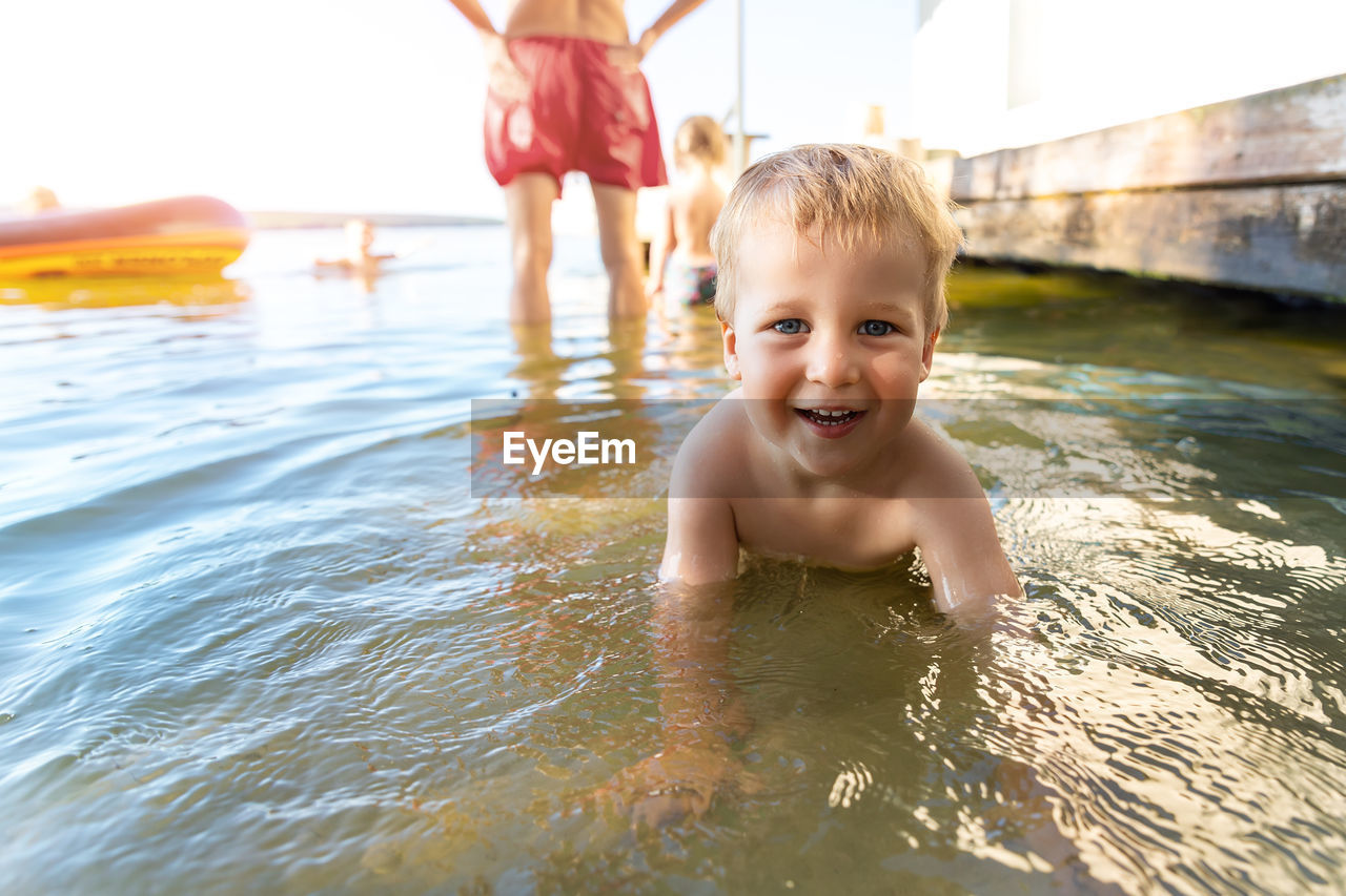 Portrait of smiling shirtless boy swimming in lake