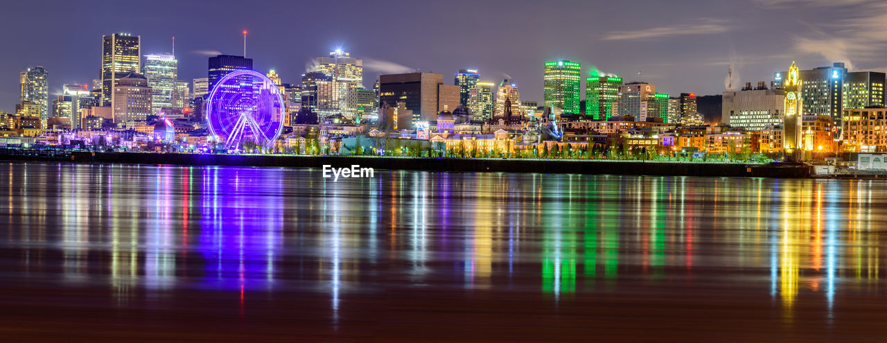ILLUMINATED BUILDINGS BY RIVER AT NIGHT