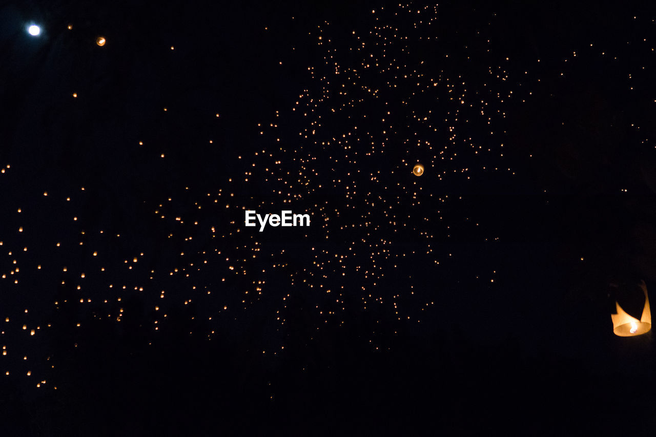 LOW ANGLE VIEW OF FIREWORKS AGAINST STAR FIELD AT NIGHT