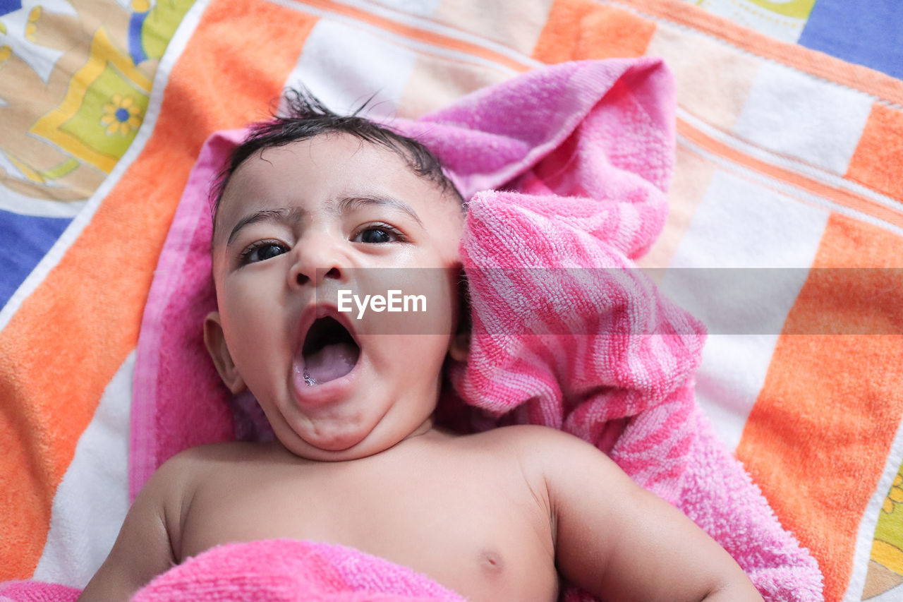 PORTRAIT OF CUTE BABY GIRL LYING IN BED