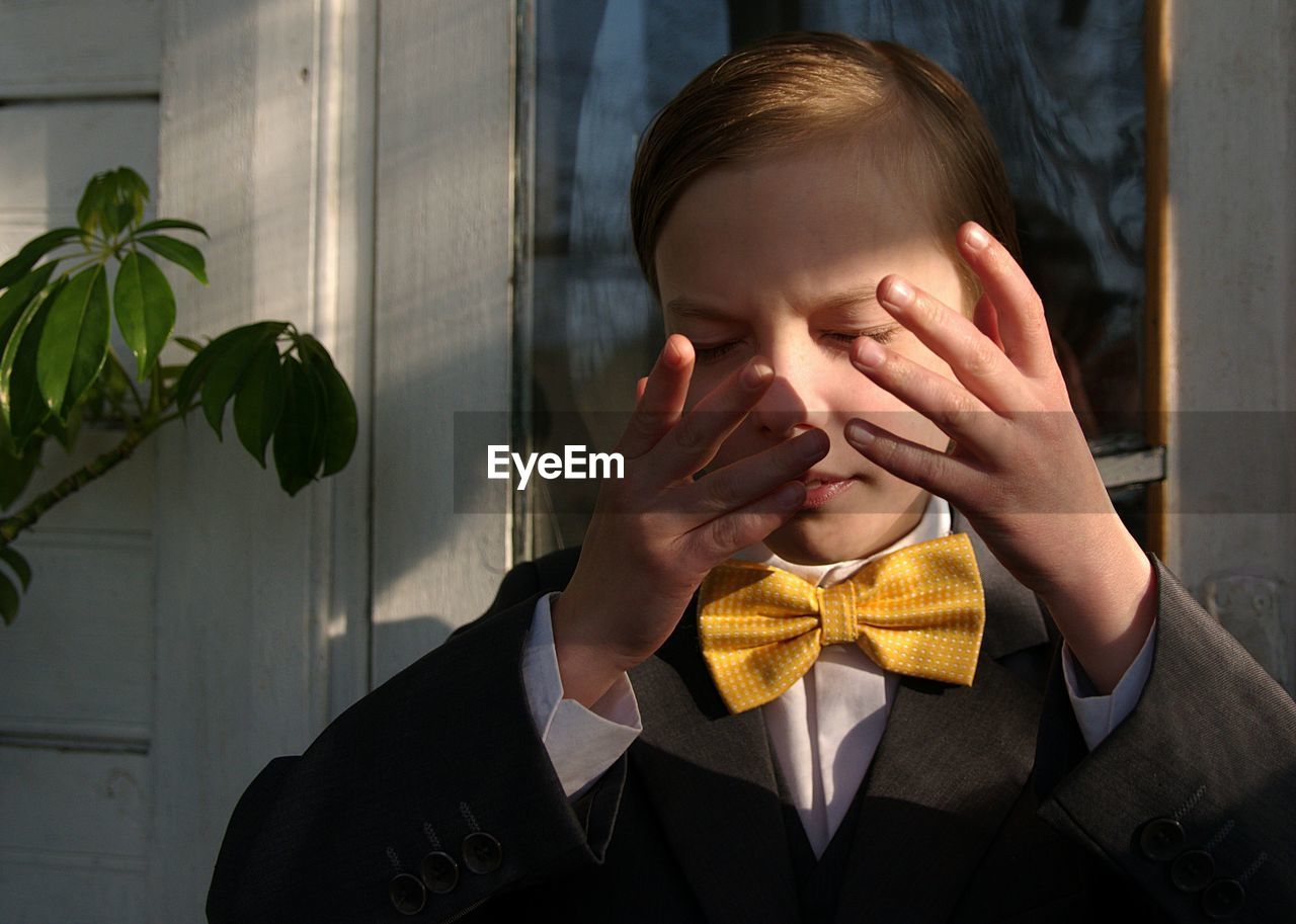 Close-up of boy rubbing eyes while standing outdoors