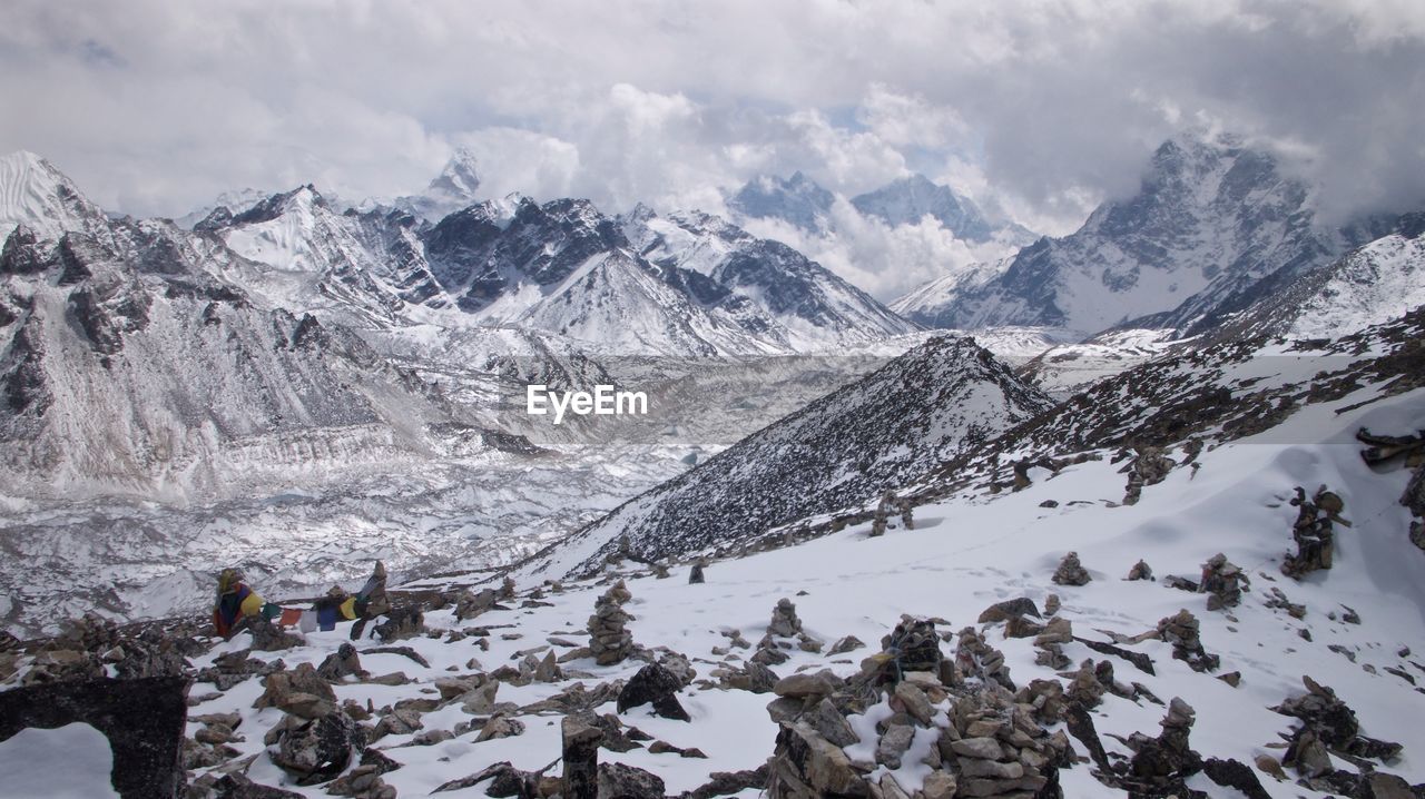 Scenic view of snow covered mountains against cloudy sky