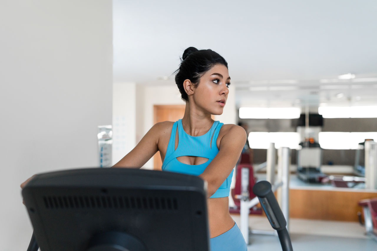 Young woman training at the gym using eliptical crosstrainer