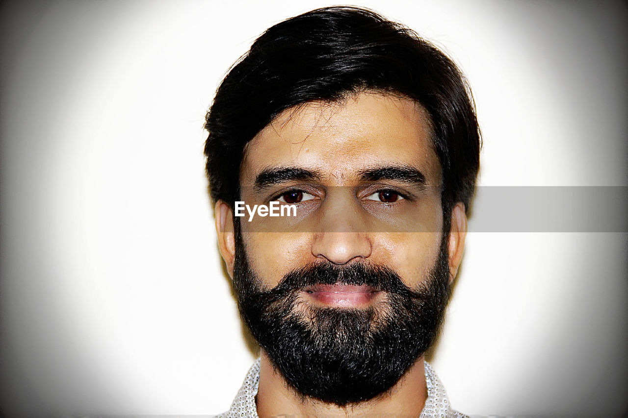 Close-up portrait of confident man against white background