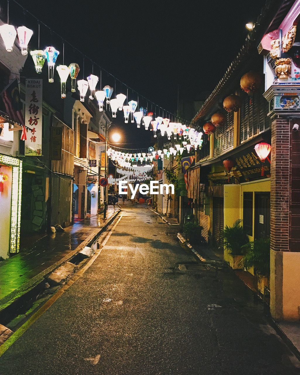 Illuminated decoration hanging amidst buildings in city at night