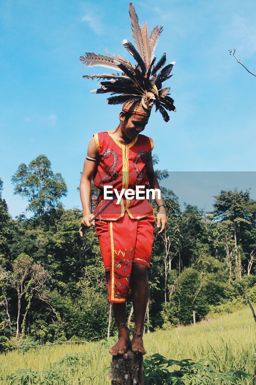 Full length of man wearing traditional clothing standing against trees