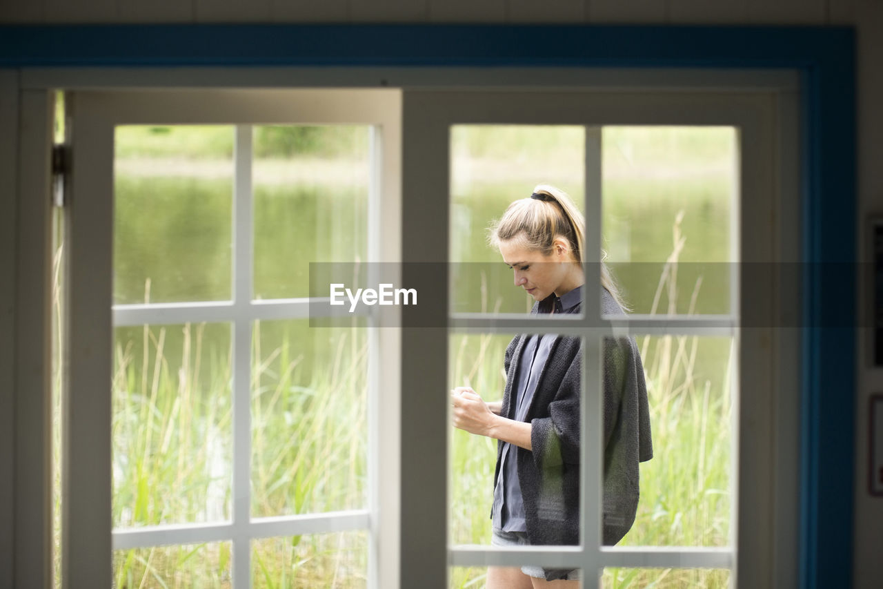 View of woman using mobile phone through door