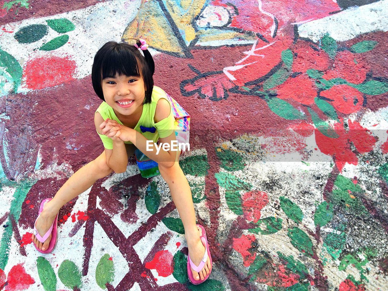 Portrait of smiling girl sitting on footpath