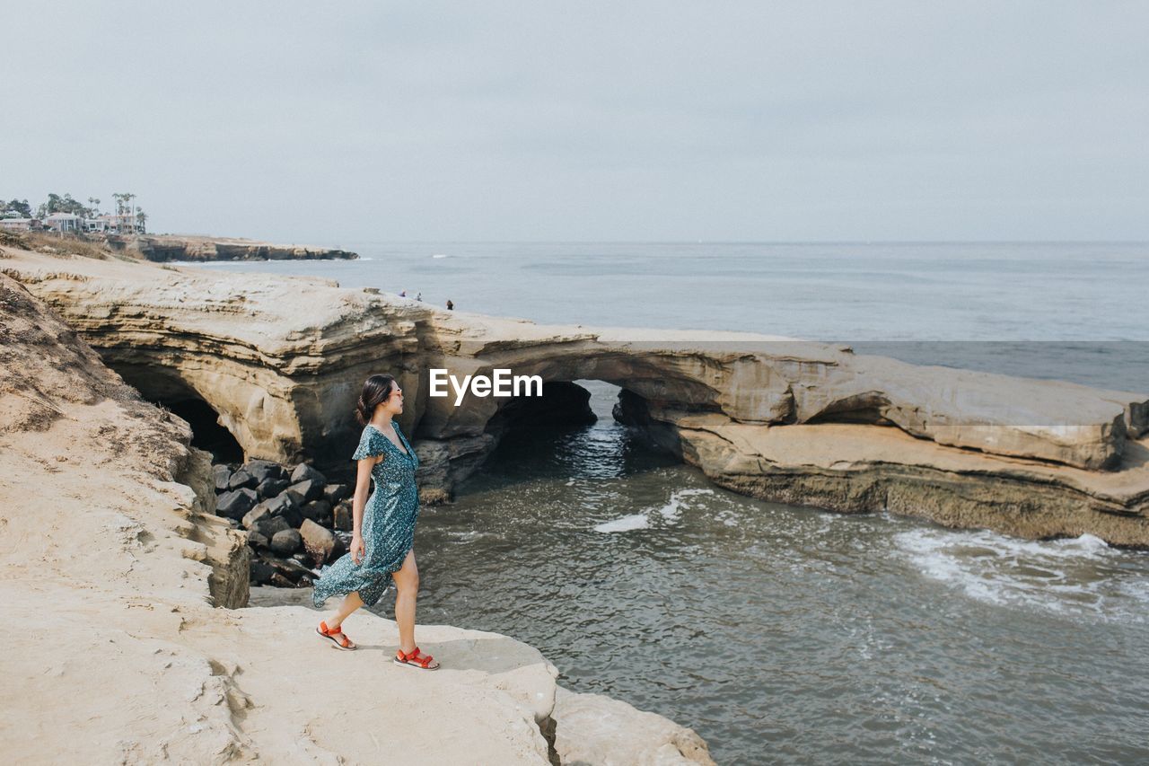 Woman walking on rock by sea