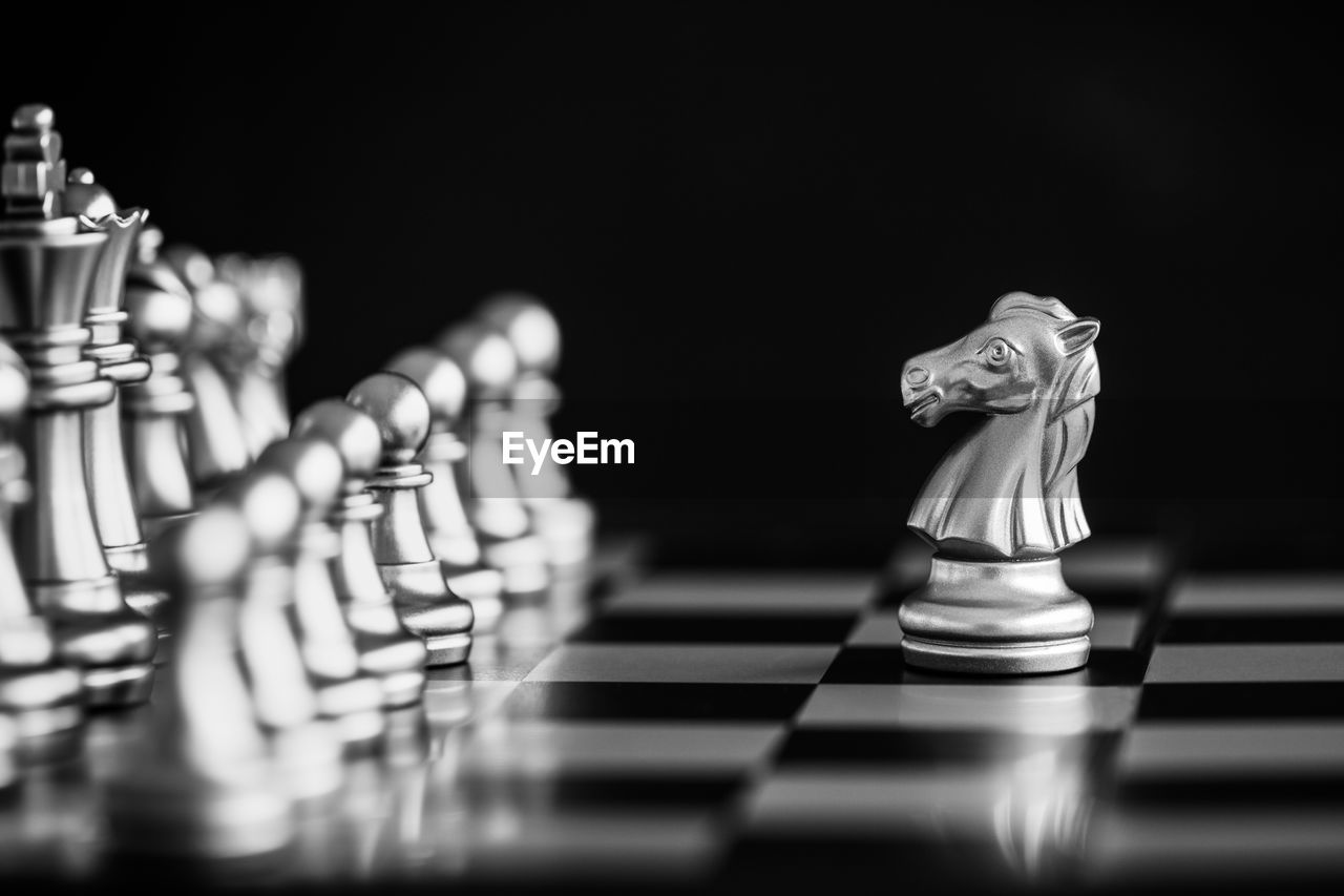 Close-up of chess pieces on board against black background