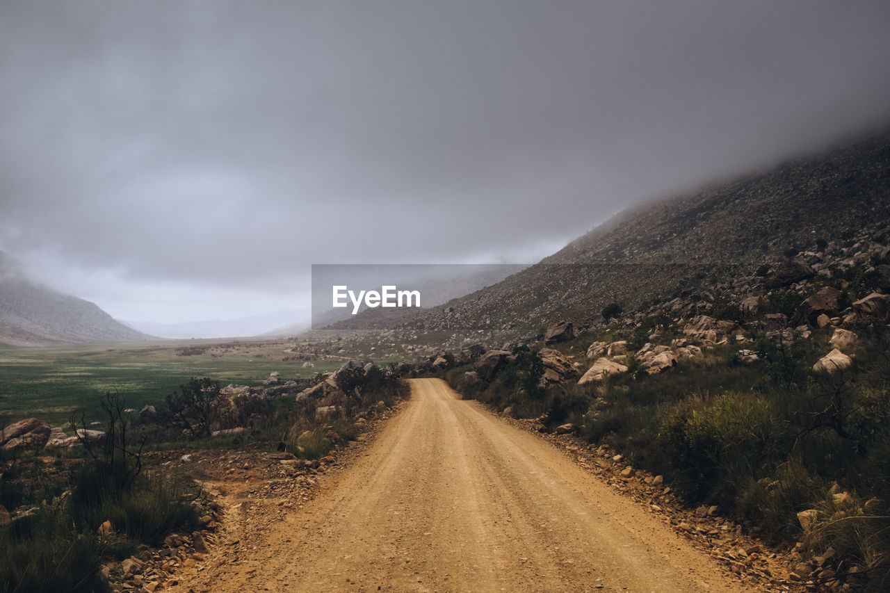 Dirt road along landscape against sky