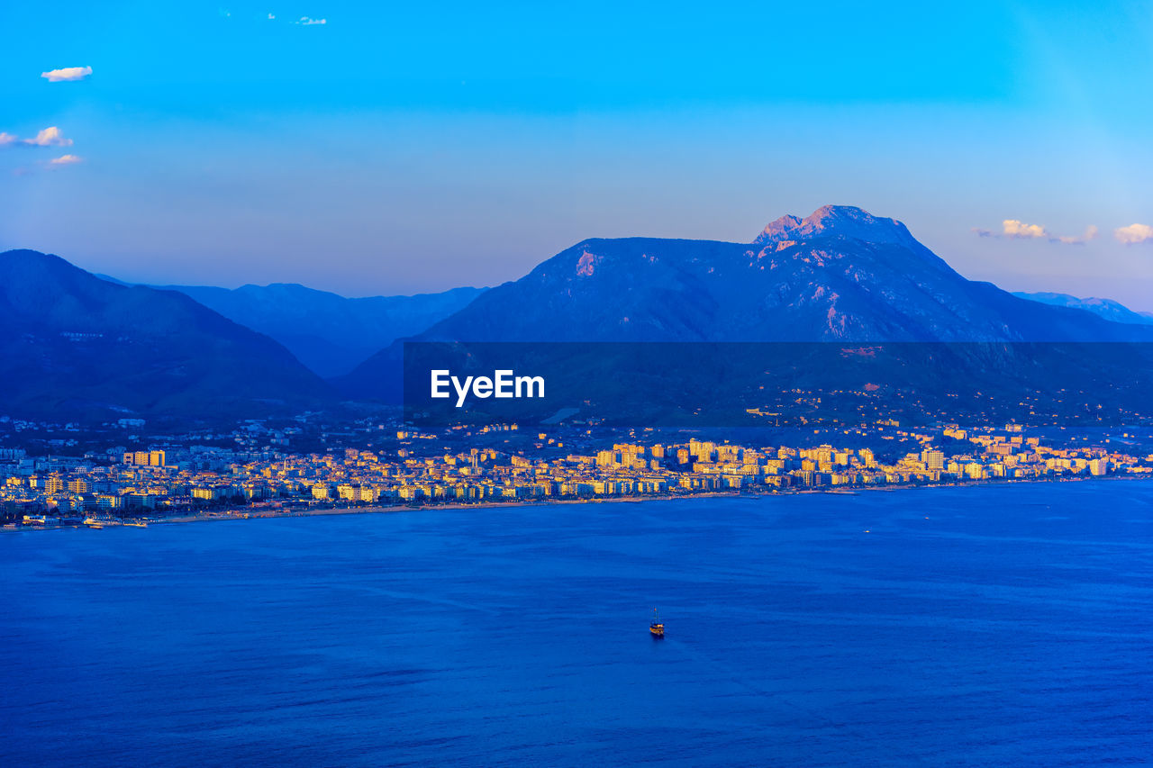 SCENIC VIEW OF SEA AND TOWN AGAINST SKY