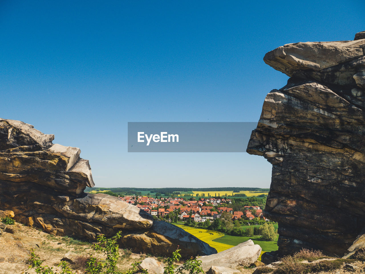 Scenic view of rock formation and buildings against clear blue sky