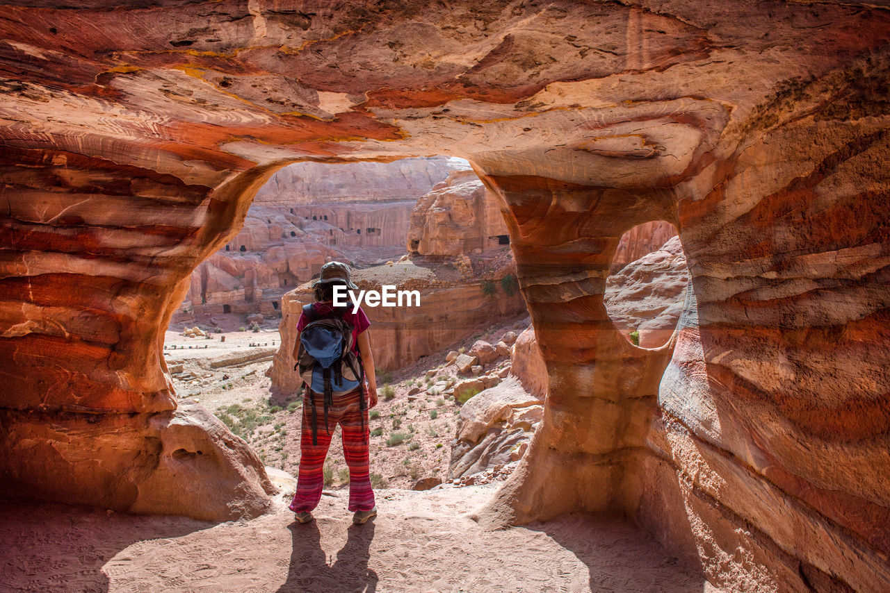 Rear view of backpacker standing on rock formation