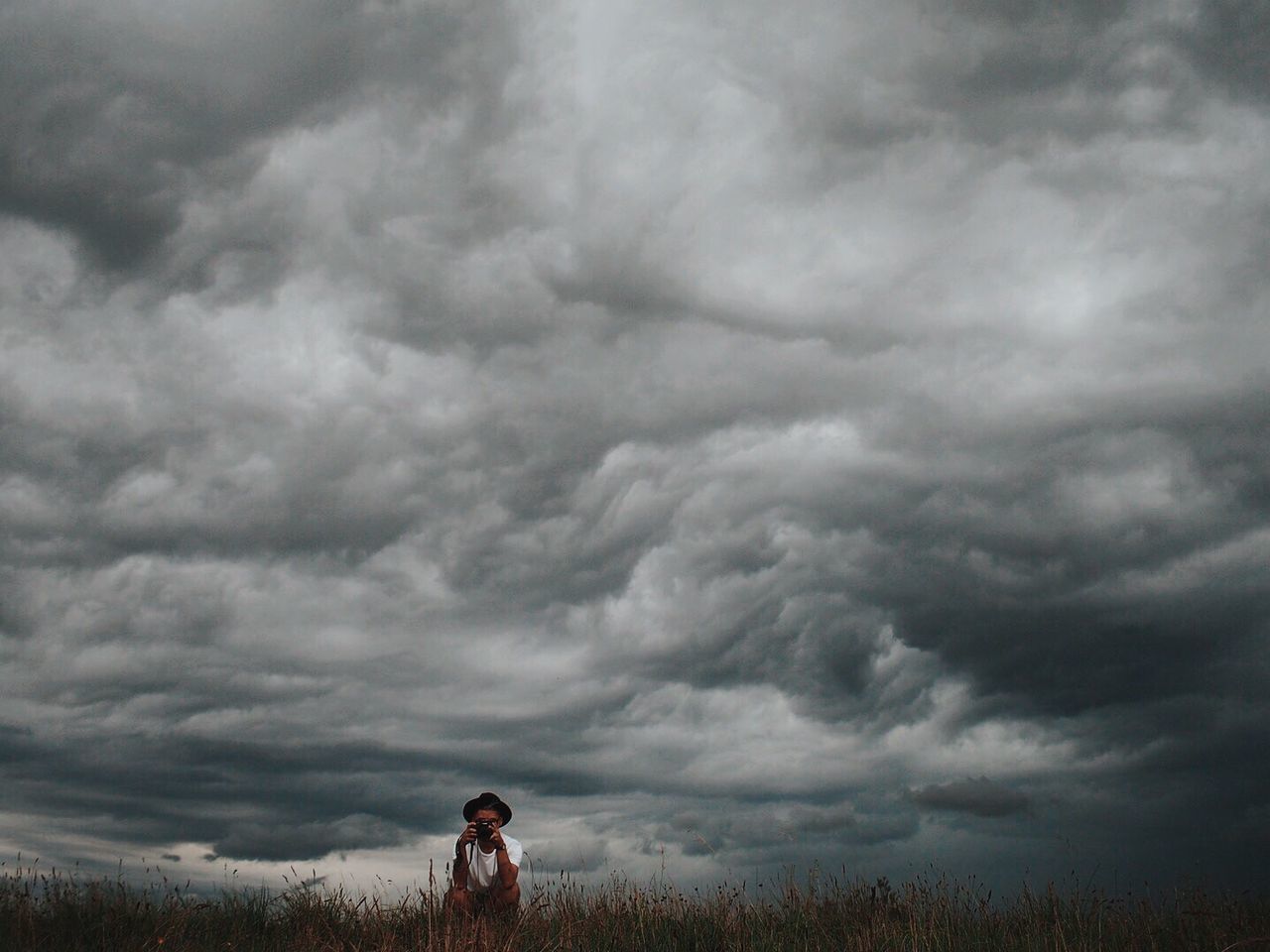 Photographer crouching against cloudy sky
