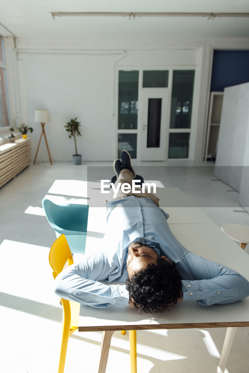 Businessman with hands behind head lying on table