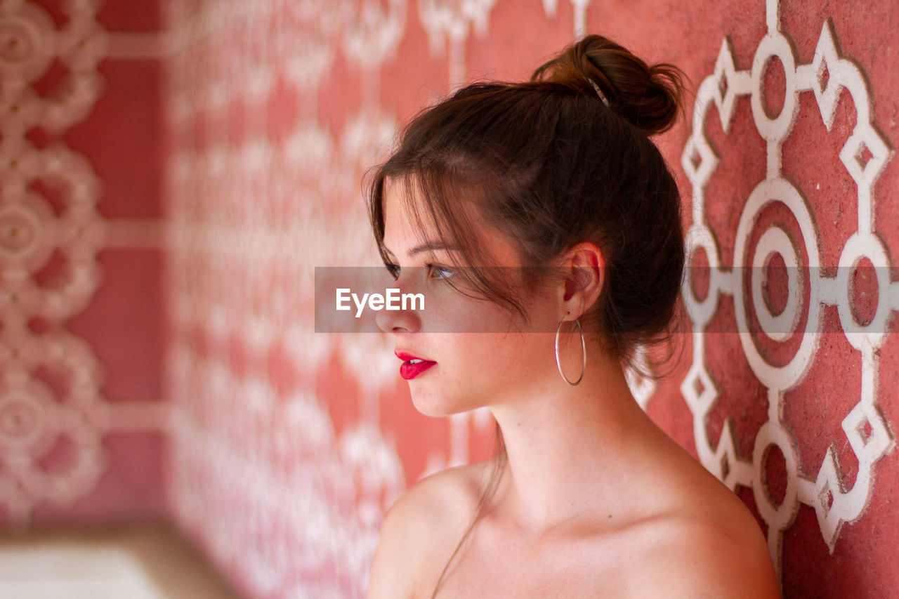 Side view of woman standing by wall