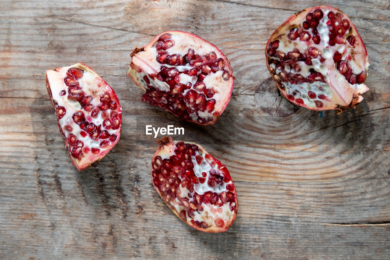 food and drink, food, wood, pomegranate, produce, freshness, healthy eating, red, fruit, plant, seed, wellbeing, no people, pomegranate seed, high angle view, indoors, table, dessert, studio shot, petal, still life, snack, slice, directly above, sweet food, close-up, flower, jewellery