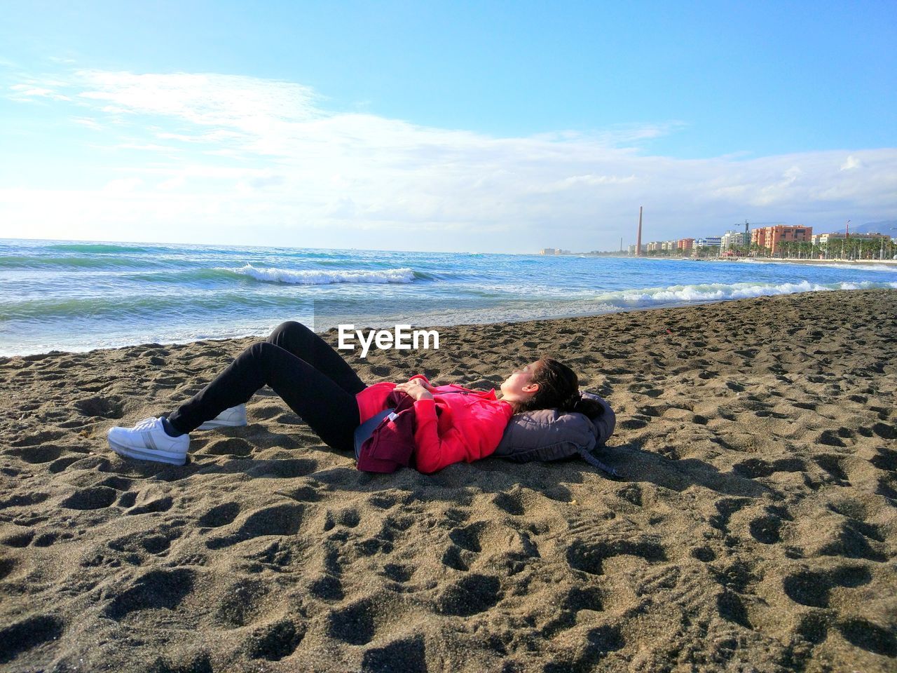 Man lying at beach against sky