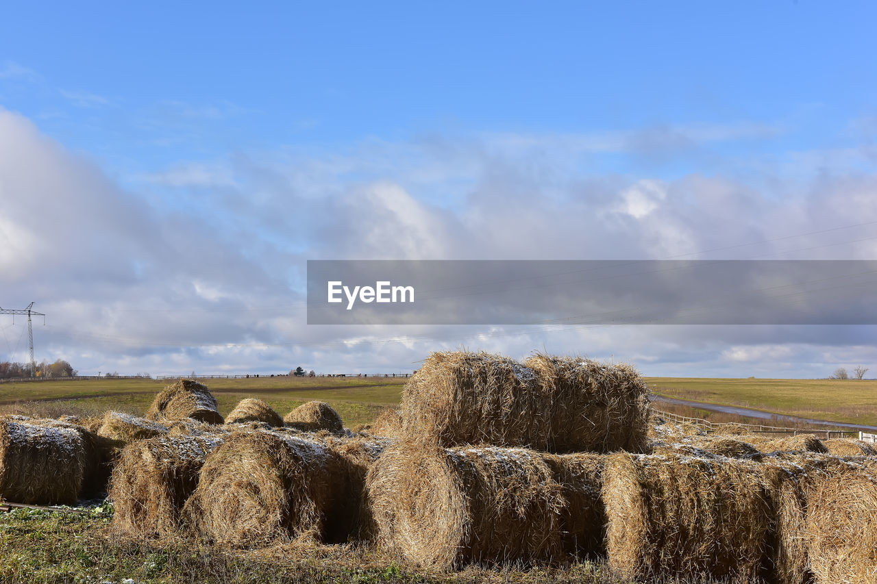 HAY BALES ON FIELD AGAINST SKY DURING SUNSET