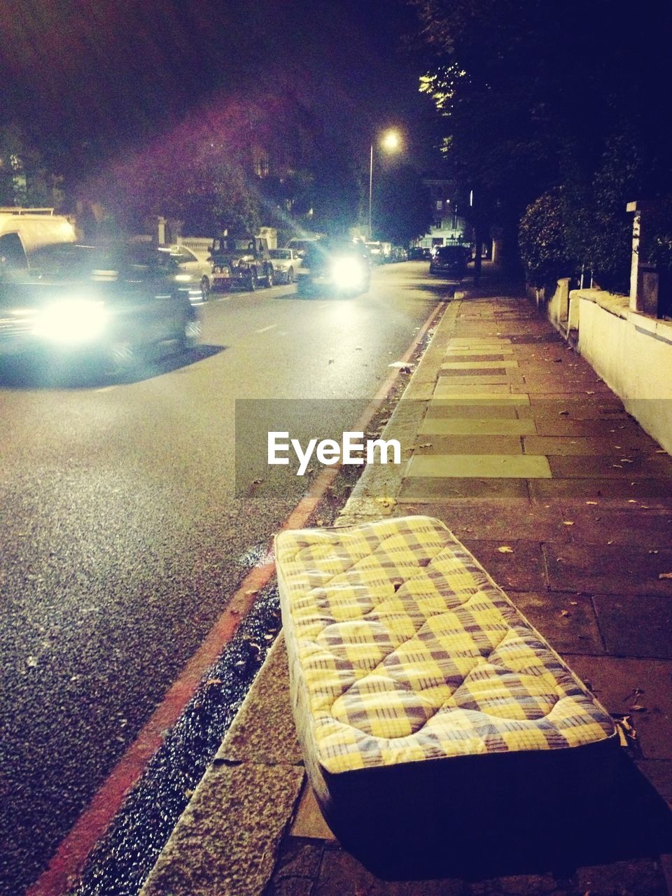 Abandoned mattress on sidewalk at night