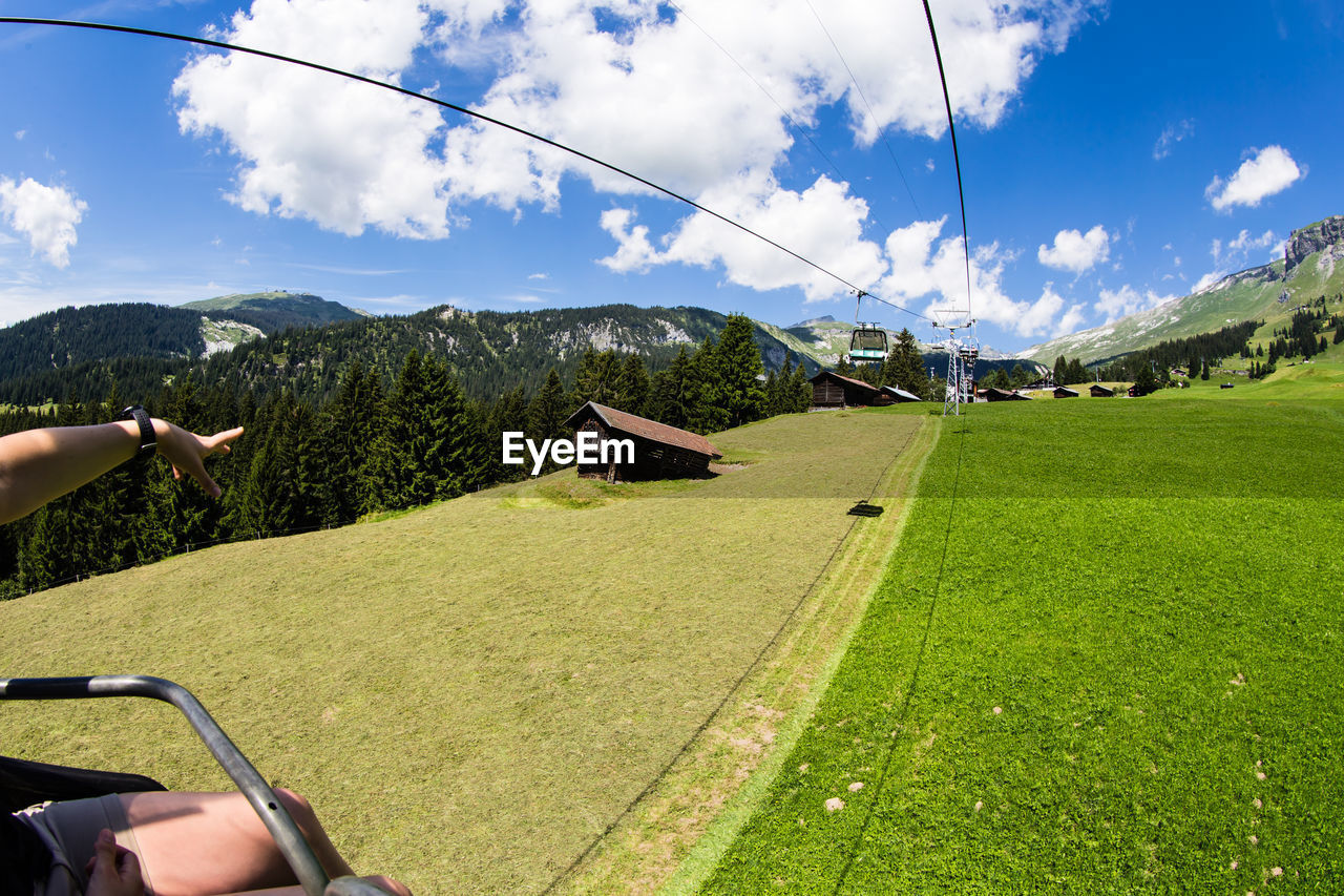 Midsection of woman sitting in cable car against sky