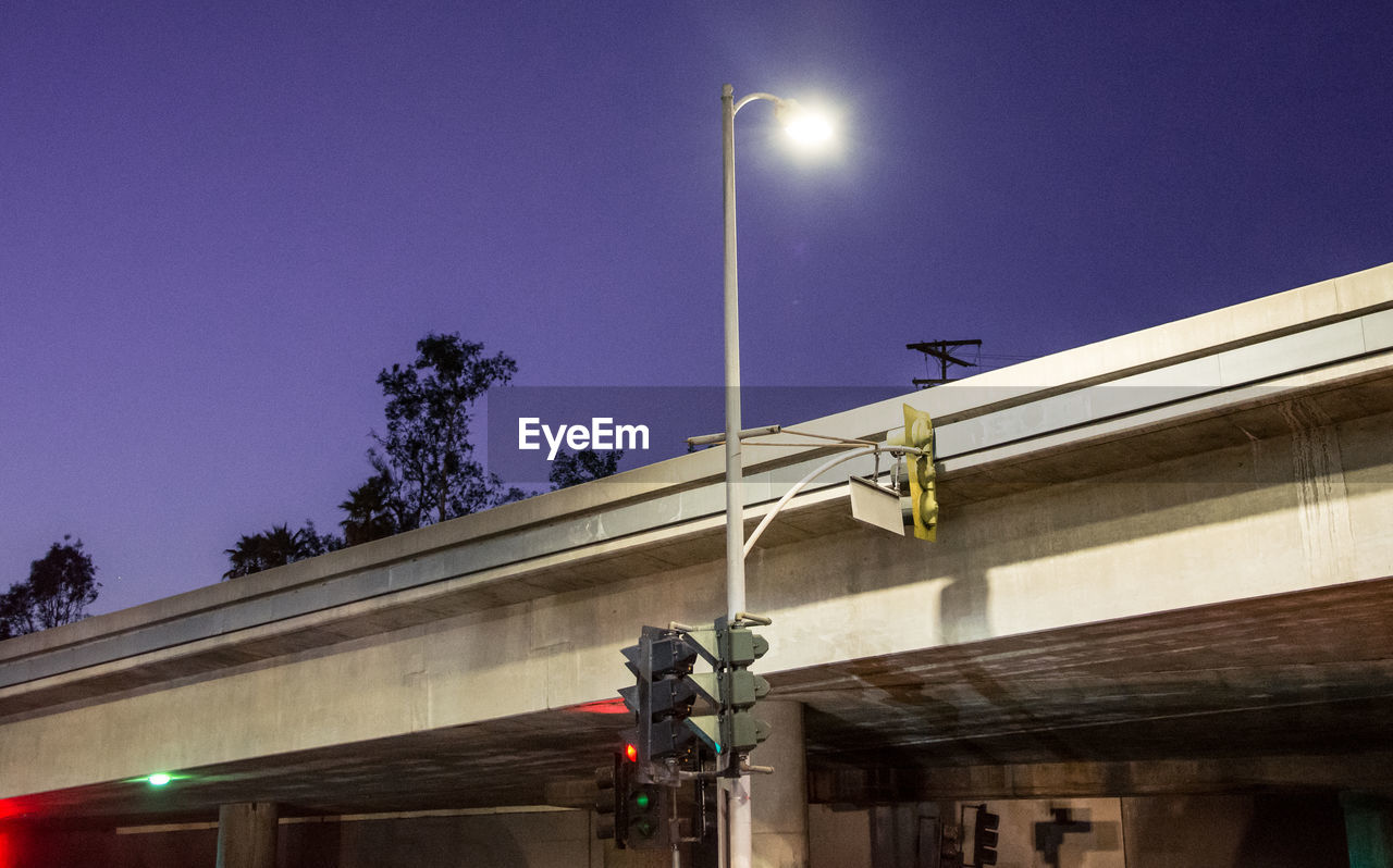 LOW ANGLE VIEW OF ILLUMINATED STREET LIGHT AGAINST BUILDING