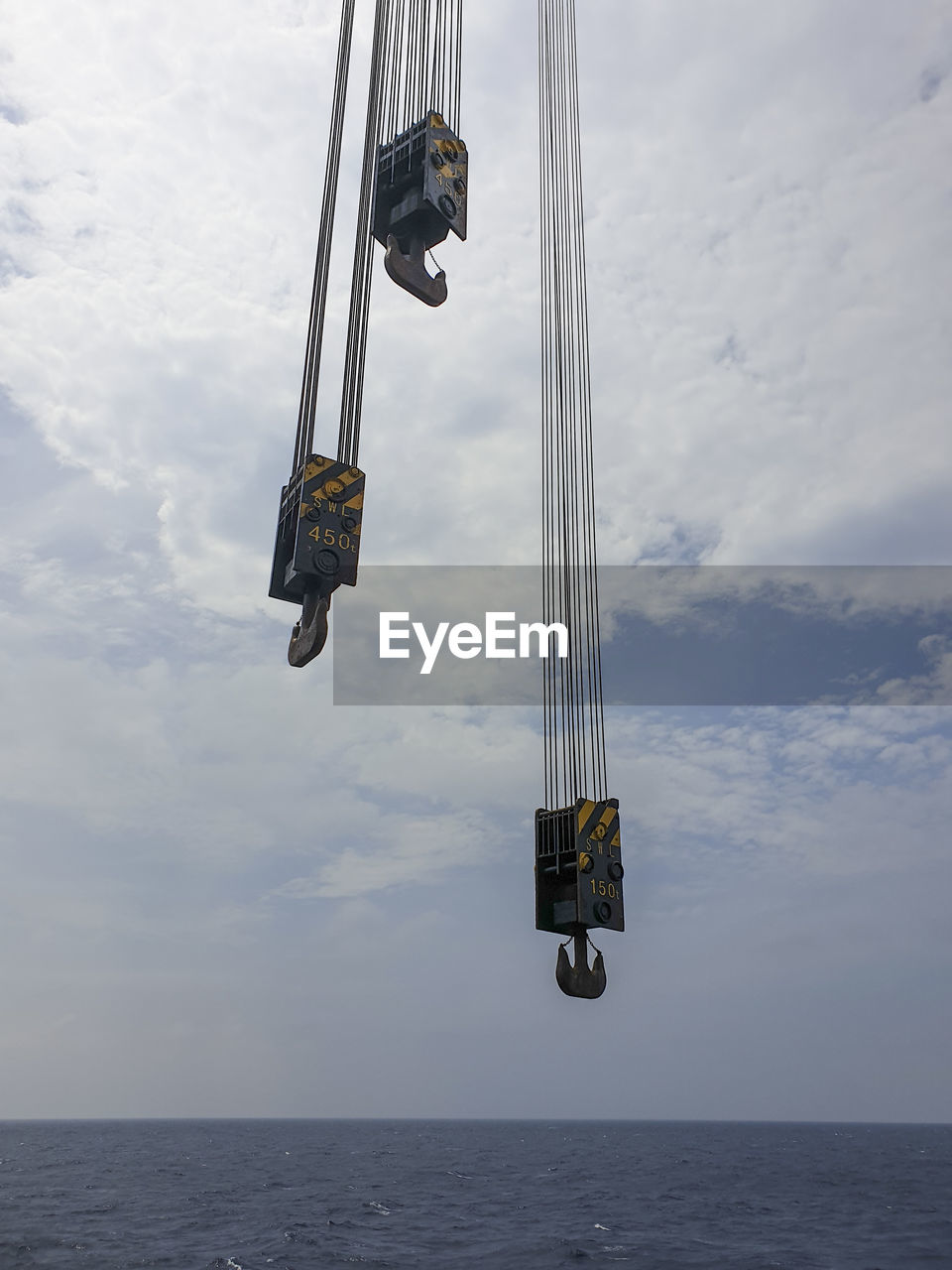 Low angle view of crane at sea against sky