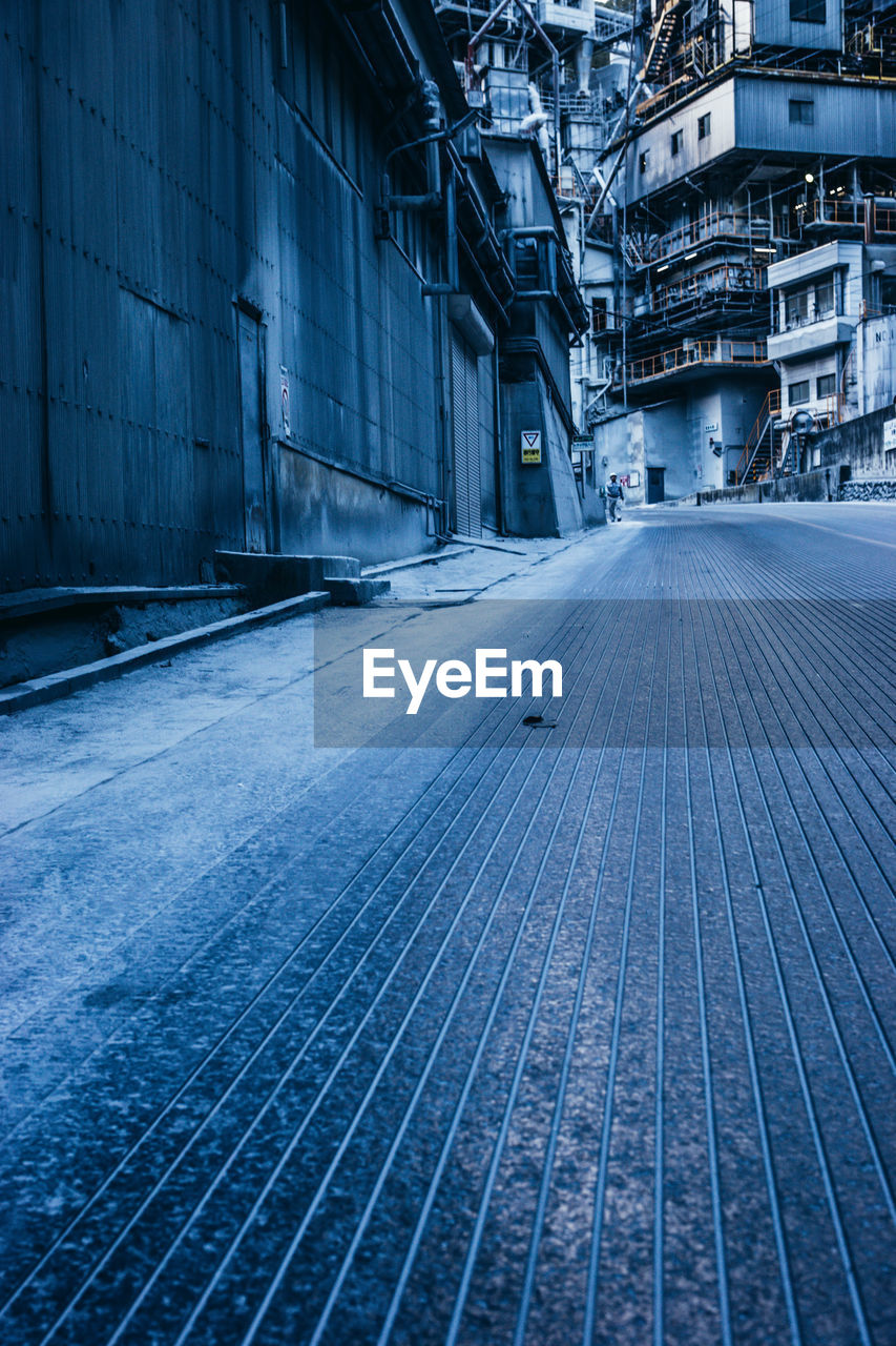 EMPTY ROAD AMIDST BUILDINGS IN CITY