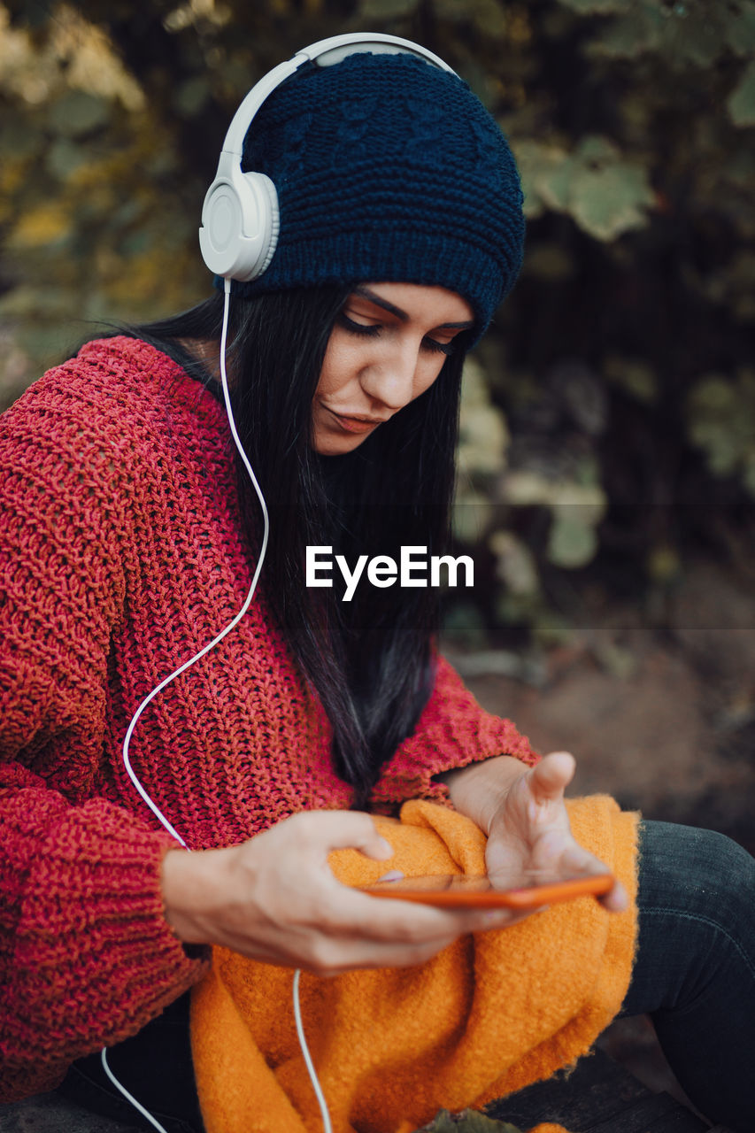 Young woman listening music with her headphones in the forest